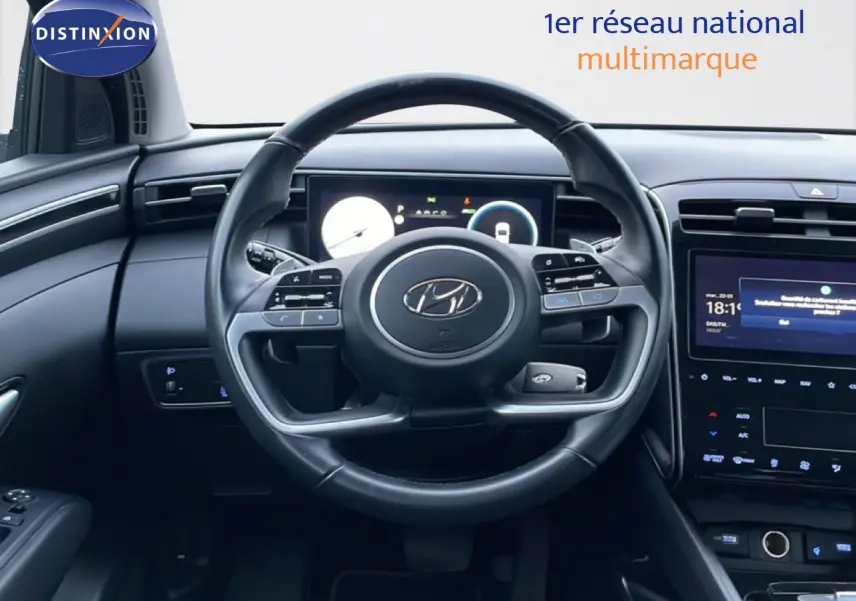 Vue intérieure centrée sur le volant cuir noir du Hyundai Tucson 2023 avec tableau de bord digital et écran tactile.