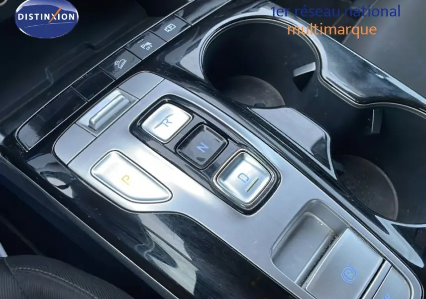 Gros plan sur la console centrale du Hyundai Tucson 2023, montrant les boutons de la boîte automatique et les porte-gobelets.