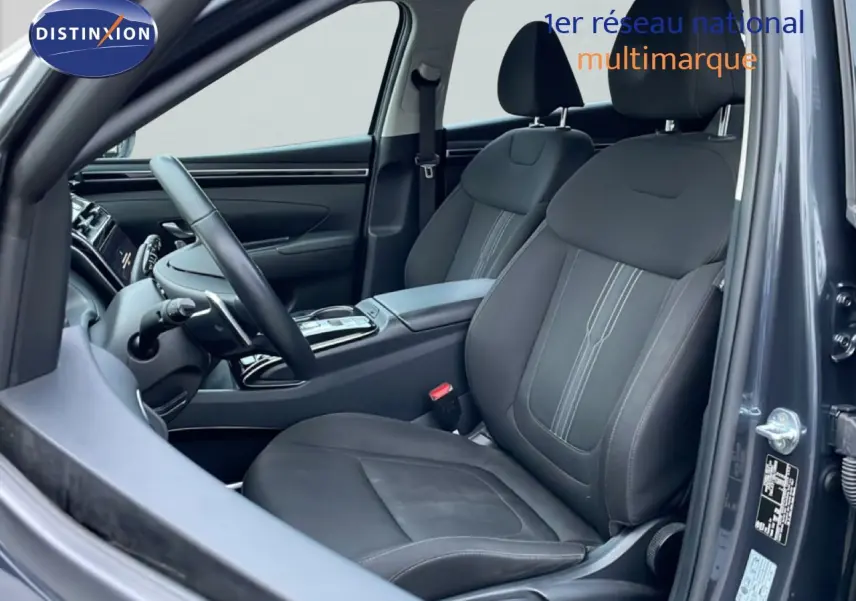 Vue intérieure côté conducteur du Hyundai Tucson 2023 en Dark Knight Metal, sièges tissu noir et volant multifonction.