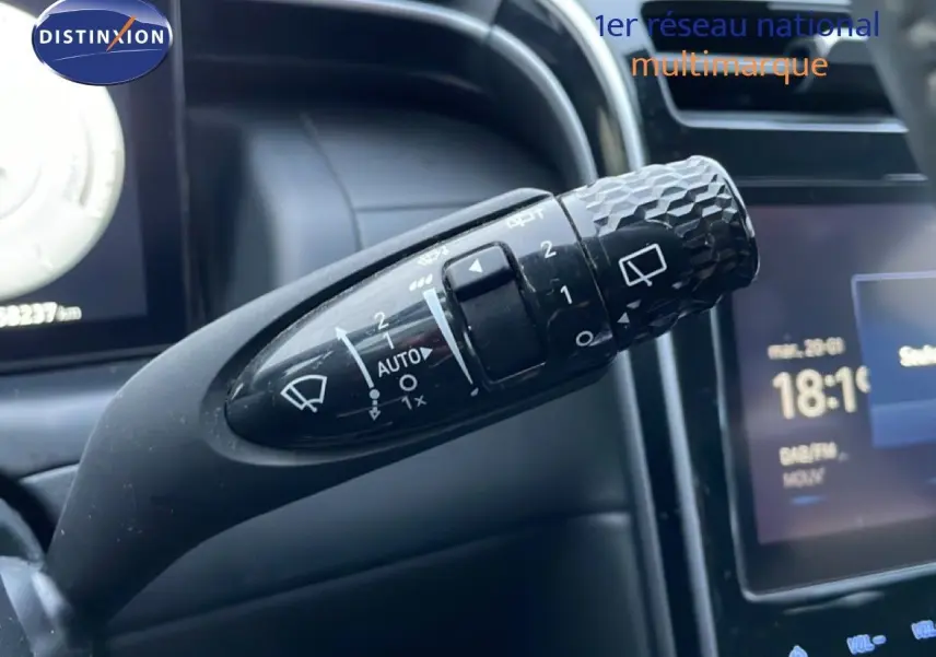 Gros plan sur la commande d’essuie-glace du Hyundai Tucson 2023, avec détails des réglages et tableau de bord en arrière-plan.