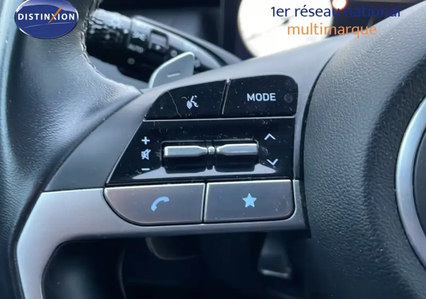 Gros plan sur les commandes gauche au volant du Hyundai Tucson 2023 en cuir noir, boutons de volume et mode visibles.
