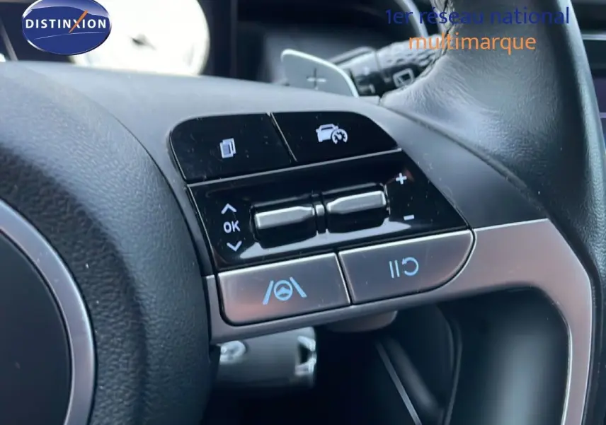 Gros plan sur les commandes au volant noir du Hyundai Tucson 2023, avec boutons de régulateur de vitesse et assistance au maintien de voie.