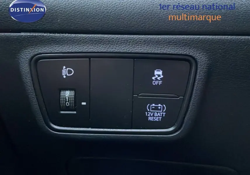 Gros plan sur les commandes intérieures noires du Hyundai Tucson 2023, avec réglage des phares et bouton de traction.