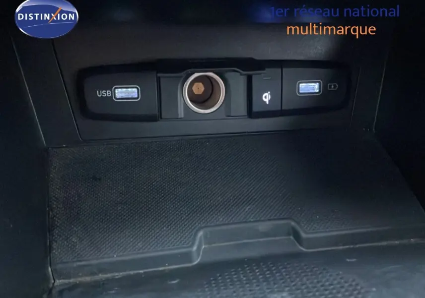 Vue rapprochée de la console centrale du Hyundai Tucson 2023, montrant les ports USB et prise 12V sur fond noir.