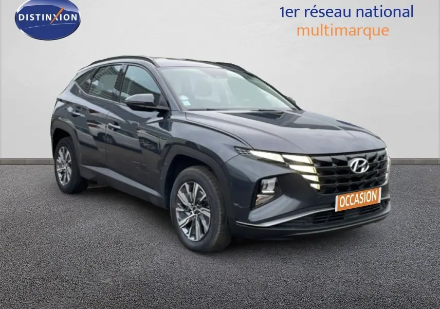 Hyundai Tucson 2023 hybride en Dark Knight Metal, vue 3/4 avant droite avec calandre et phares allumés.