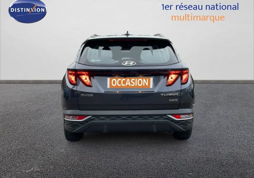 Vue arrière d'un Hyundai Tucson hybride 2023 en Dark Knight Metal avec feux LED allumés sur fond neutre.