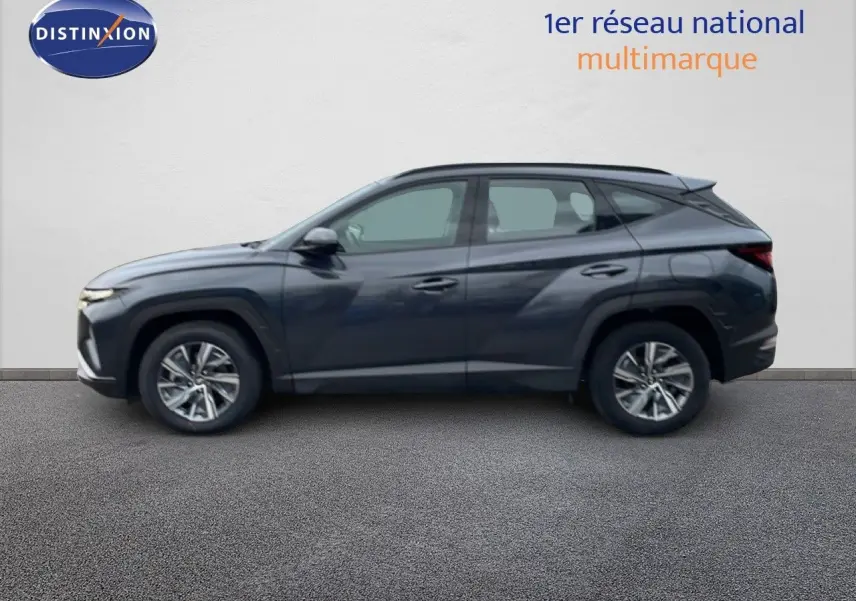 Vue de profil côté gauche d'un Hyundai Tucson 2023 hybride en couleur Dark Knight Metal, avec jantes alliage et lignes anguleuses.