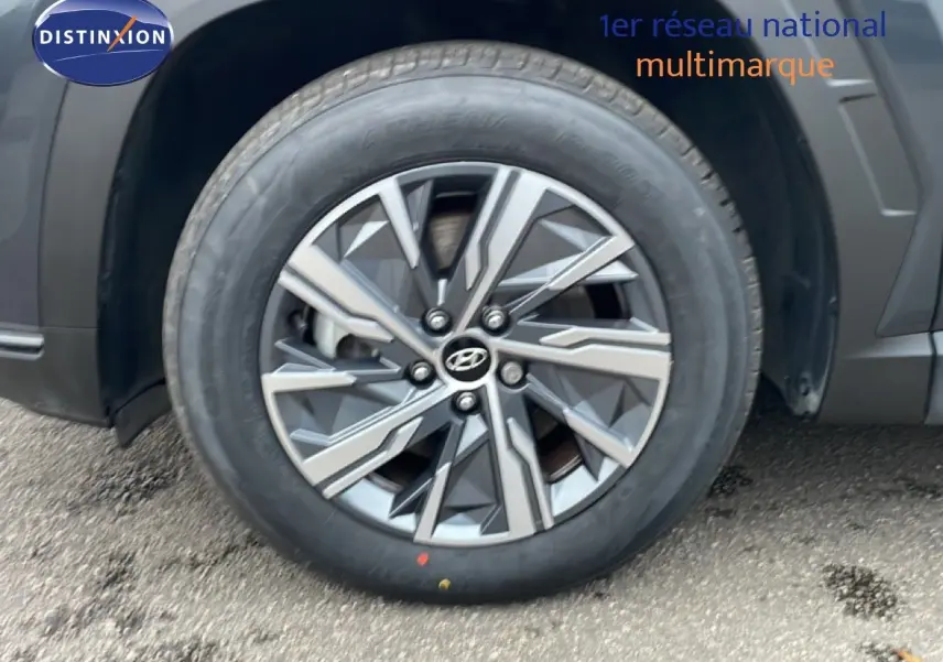 Gros plan sur la roue avant gauche du Hyundai Tucson 2023 Dark Knight Metal avec jante alliage bicolore.