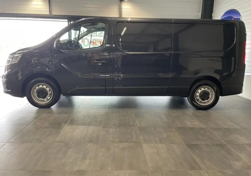 Vue de profil côté gauche du Renault Trafic Fourgon gris Comète avec jantes tôles et porte coulissante visible.
