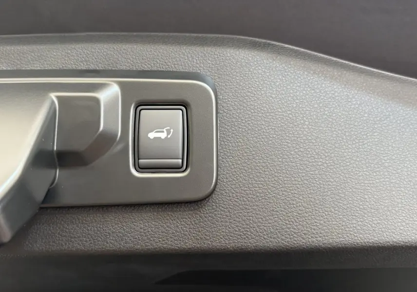 Gros plan sur le bouton d'ouverture électrique du coffre dans l'habitacle du Renault Espace blanc 2025.