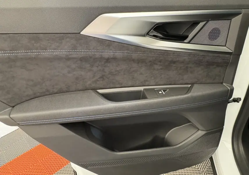 Vue rapprochée de la porte avant gauche du Renault Espace blanc, intérieur noir avec surpiqûres bleues et insert tissu.