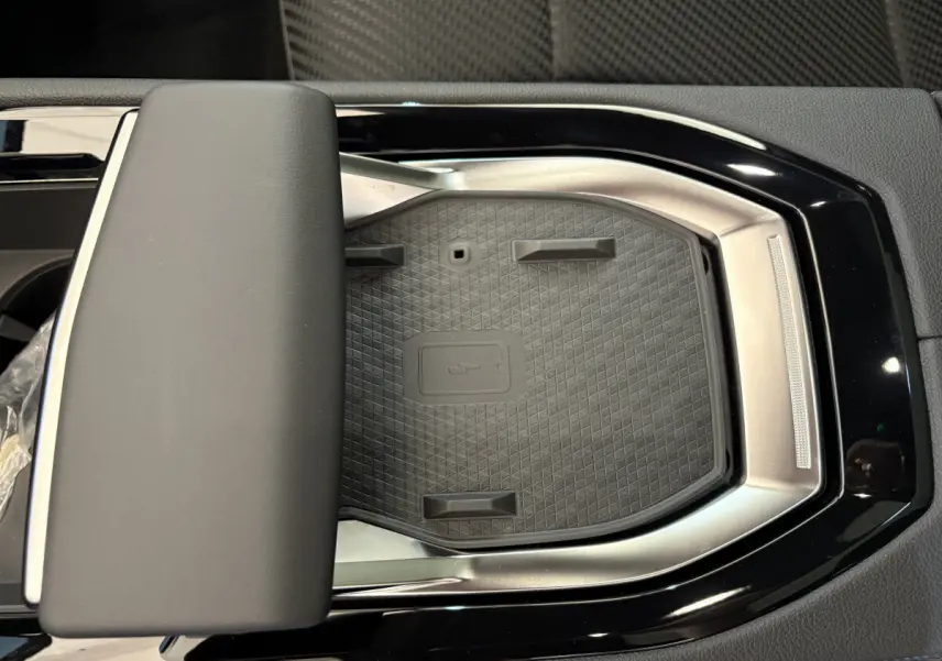 Gros plan sur la zone de recharge à induction noire et argentée au centre de la console d'une Renault Espace blanche.