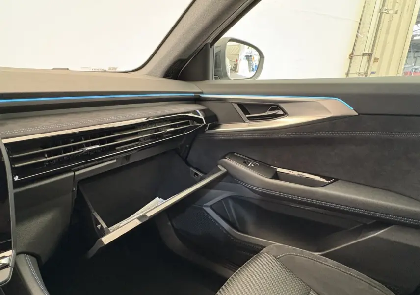 Intérieur côté passager du Renault Espace 2025 esprit Alpine, boîte à gants ouverte, finition noire avec éclairage bleu.