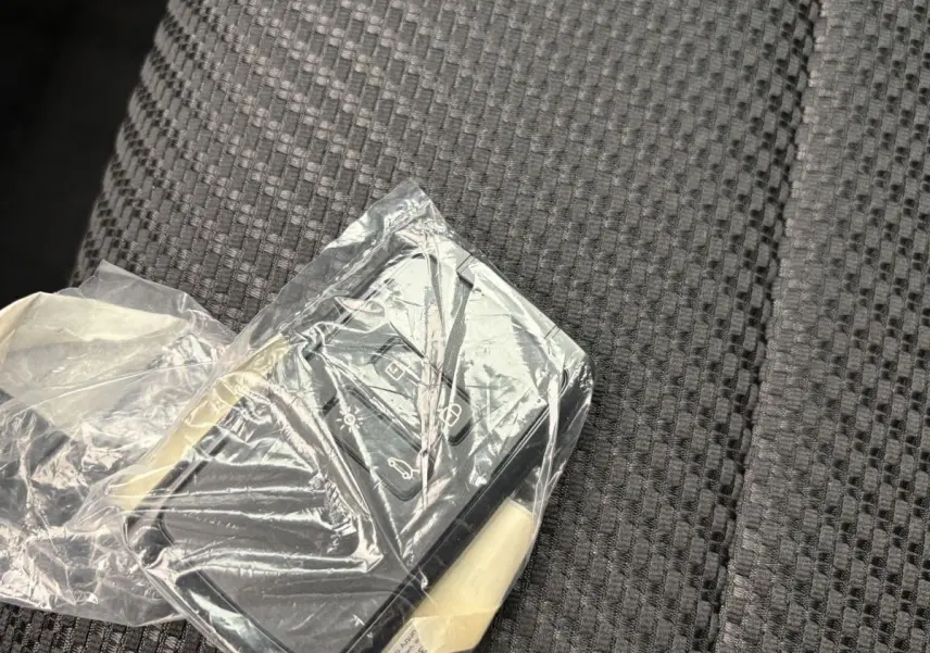 Télécommande Renault Espace 2025 en plastique transparent posée sur un siège tissu gris foncé à motifs.