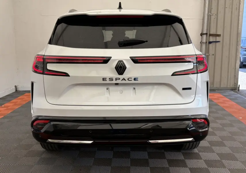 Vue arrière d'un Renault Espace blanc 2025 avec feux LED allumés et pare-chocs noir brillant dans un garage.