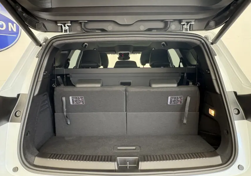 Coffre ouvert vue arrière d’un Renault Espace blanc avec sièges rabattus et banquette arrière visible.