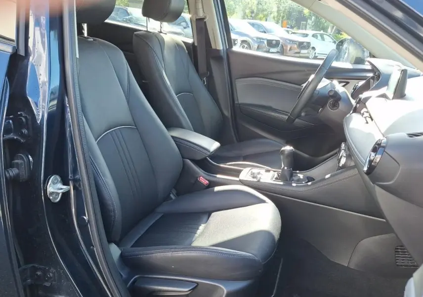 Vue intérieure côté conducteur du Mazda CX-3 bleu 2021, sièges en cuir noir et console centrale avec boîte manuelle.