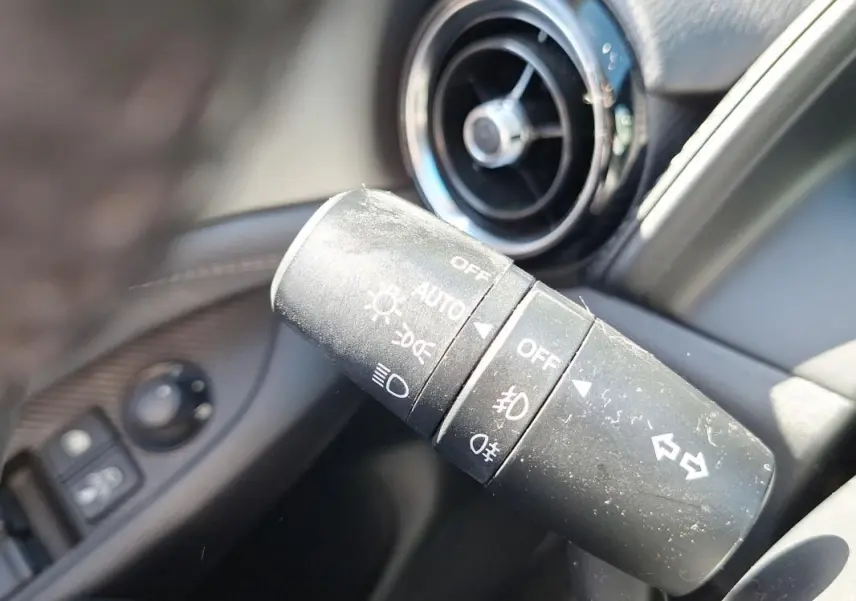 Gros plan sur la commande des phares et clignotants du Mazda CX-3 2021, avec aérateur circulaire en arrière-plan.