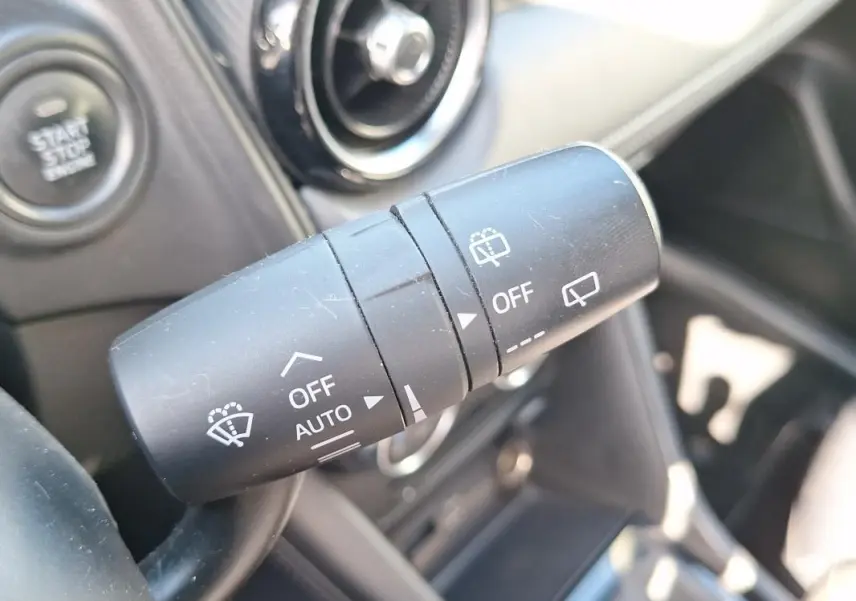 Gros plan sur la commande des essuie-glaces du Mazda CX-3 2021, avec bouton start/stop visible en arrière-plan.