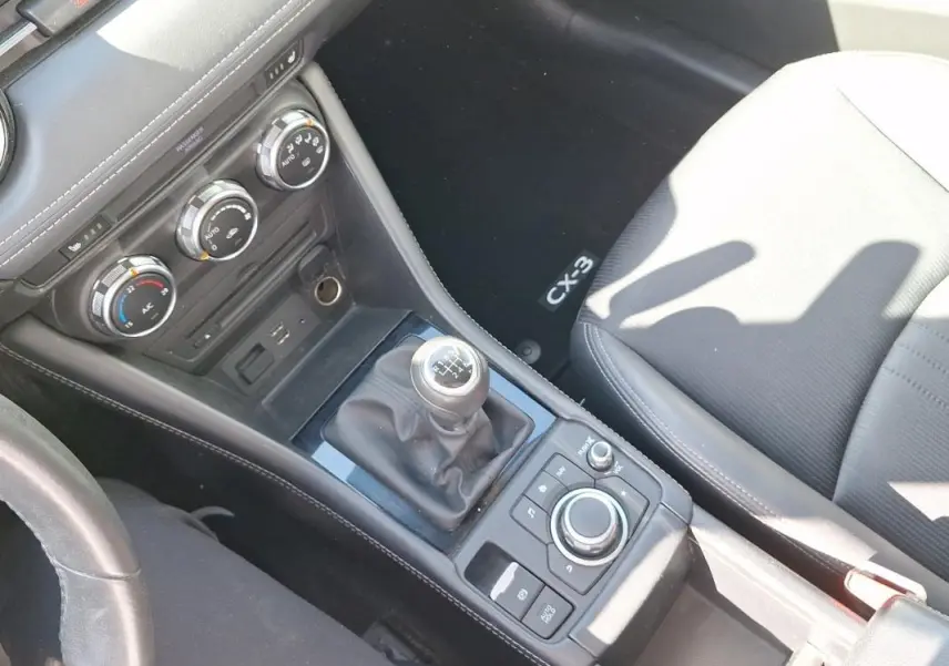 Vue intérieure en plongée du levier de vitesse manuel et console centrale noire du Mazda CX-3 2021.