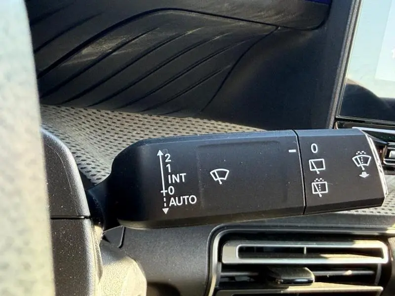 Gros plan sur la commande d'essuie-glace à gauche du volant dans l'habitacle de la Citroën C3 2025 noir Perla Nera.