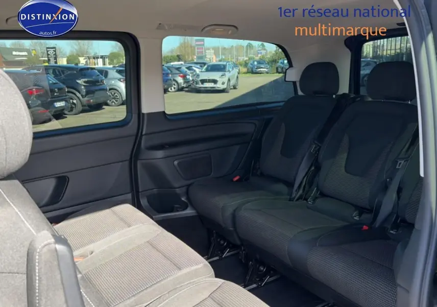 Vue intérieure sur les sièges arrière en tissu noir du Mercedes Classe V 220 d long style, avec porte latérale coulissante ouverte.