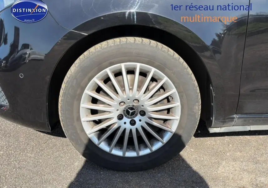 Gros plan sur la roue arrière gauche argentée d’un Mercedes Classe V noir avec jante multi-branches.