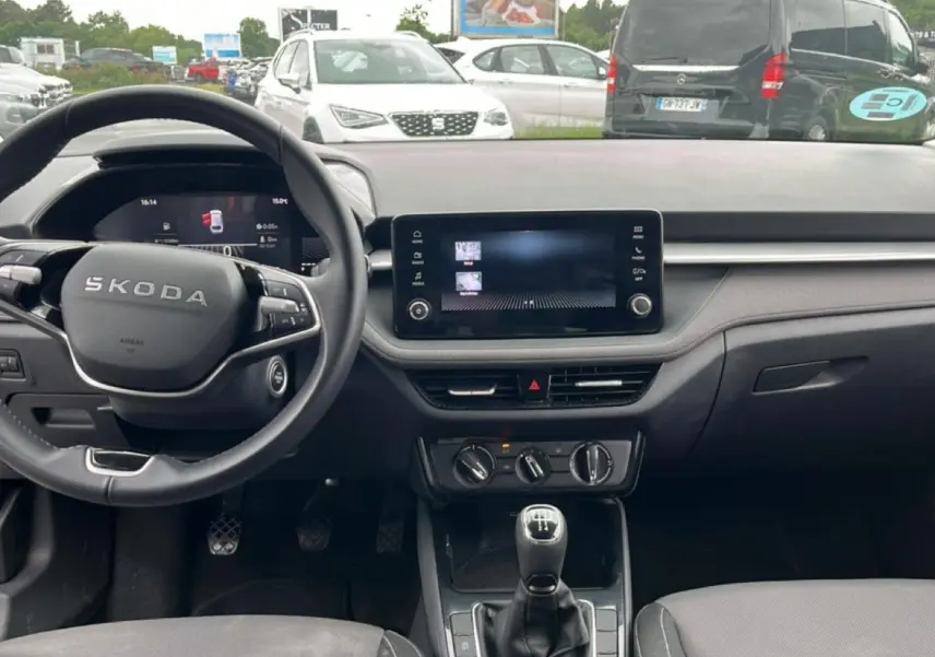 Vue intérieure de face du tableau de bord et volant cuir noir d'une Skoda Fabia 2025 avec écran tactile et levier de vitesses manuel.