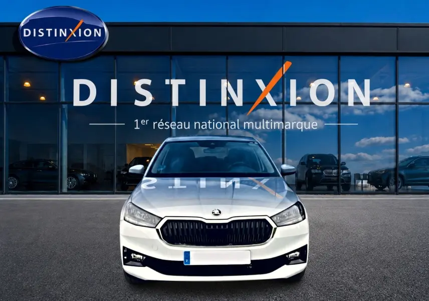 Vue frontale d'une Skoda Fabia blanche 2025 garée devant une vitrine avec logo Distinxion.