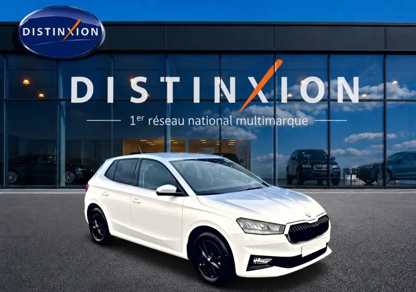 Skoda Fabia blanche vue en 3/4 avant droit, avec jantes noires et calandre distinctive devant showroom Distinxion.