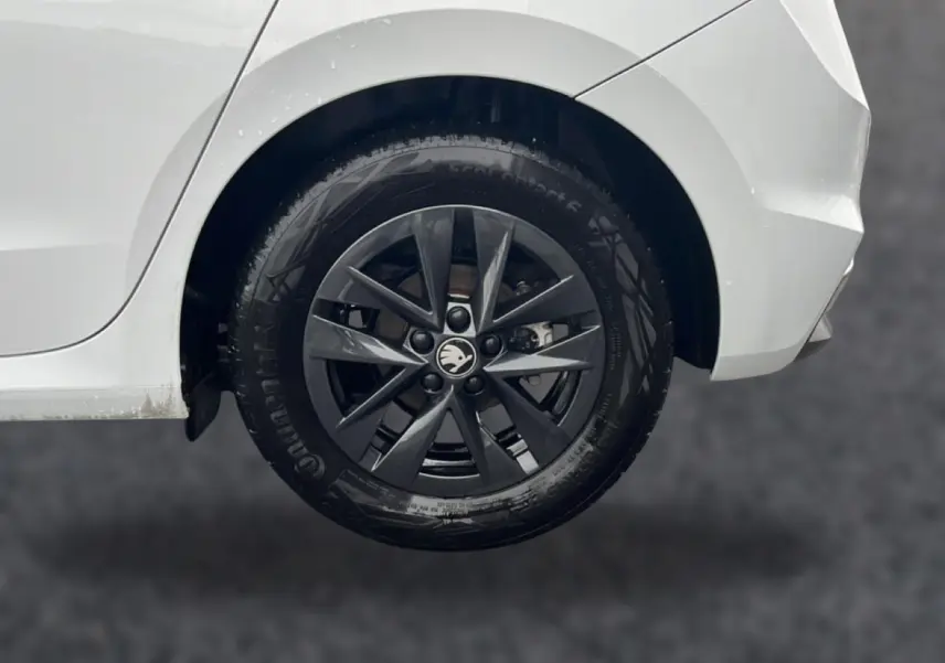 Gros plan sur la roue arrière droite noire avec jante alu gris foncé d'une Skoda Fabia blanche 2025.