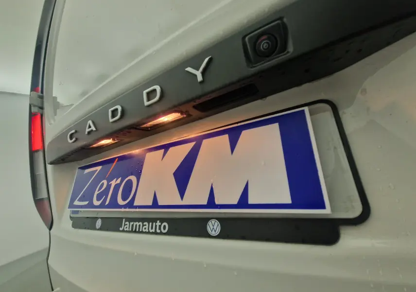 Gros plan sur l'arrière blanc d'un Volkswagen Caddy Maxi avec caméra de recul et éclairage plaque visible.