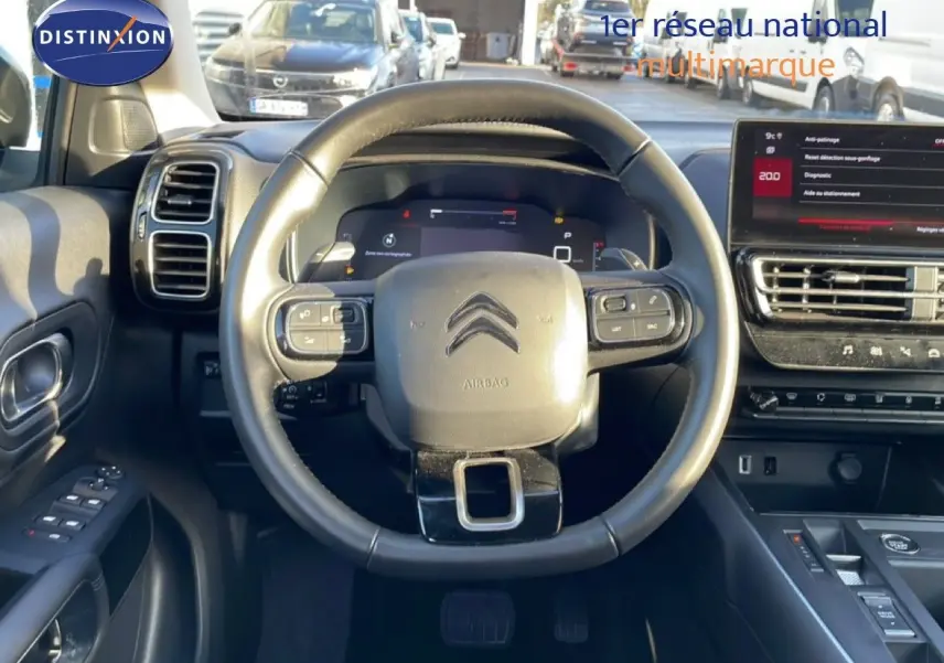 Vue intérieure centrée sur le volant cuir noir d'une Citroën C5 Aircross 2025, avec tableau de bord digital et écran tactile.