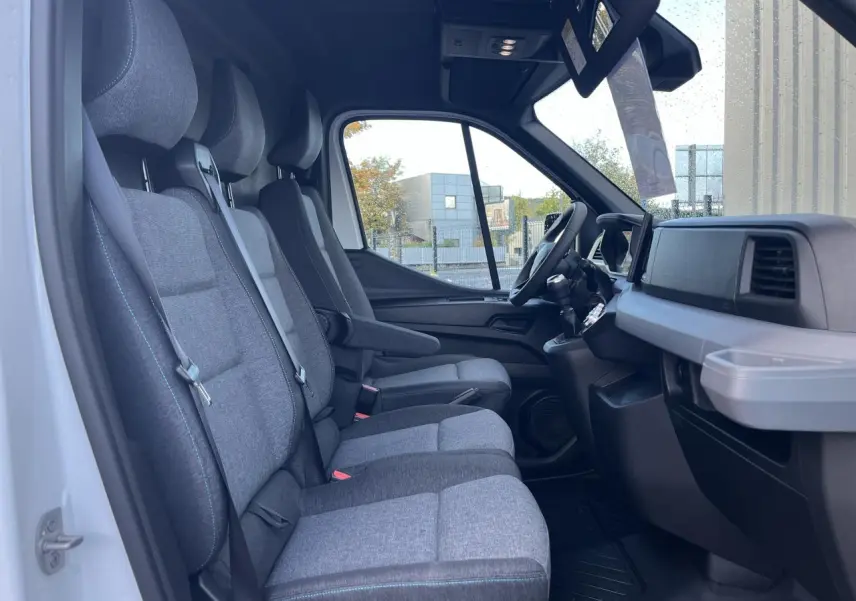 Vue intérieure côté droit du Renault Master 2025, montrant la banquette 3 places en tissu gris avec surpiqûres bleues.