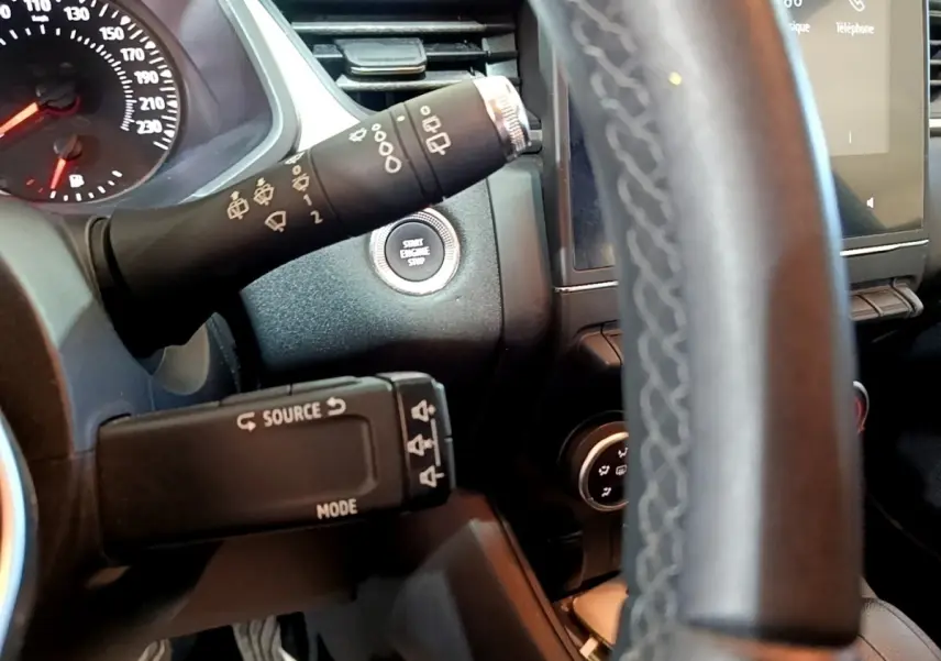 Gros plan sur le volant multifonctions noir et le tableau de bord avec bouton start/stop du Renault Captur Business 2021.