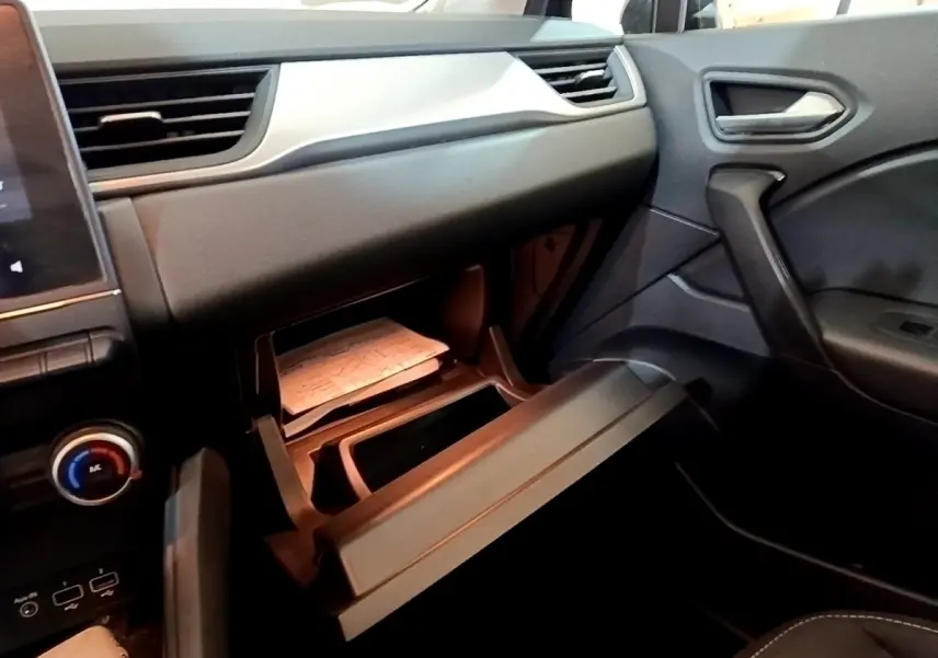 Intérieur noir du Renault Captur 2021 vu côté passager, boîte à gants ouverte avec documents visibles.