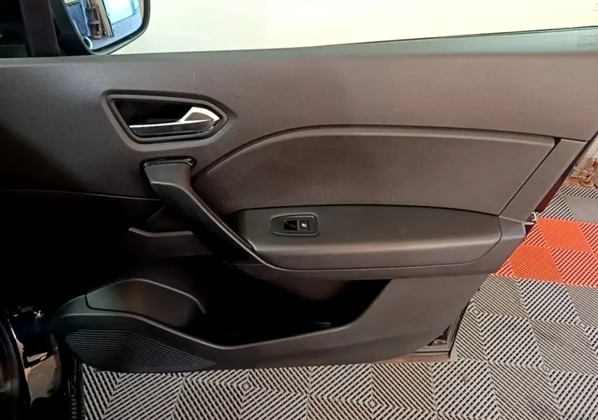 Vue intérieure côté gauche de la porte noire du Renault Captur 2021 avec poignée et commande de fenêtre électrique.