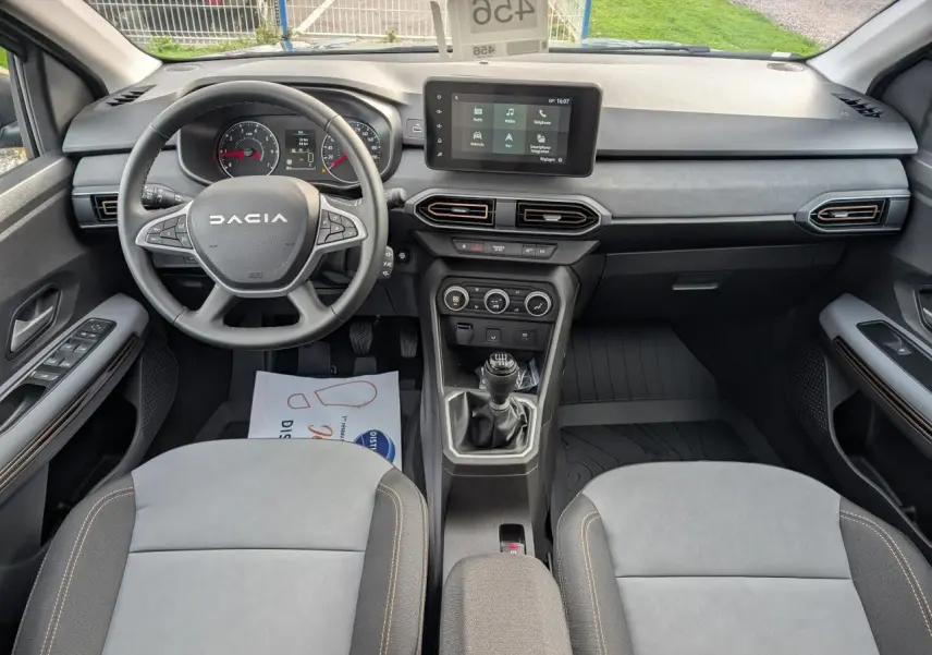 Vue intérieure avant du Dacia Jogger 2025, tableau de bord gris avec volant multifonction et boîte manuelle.