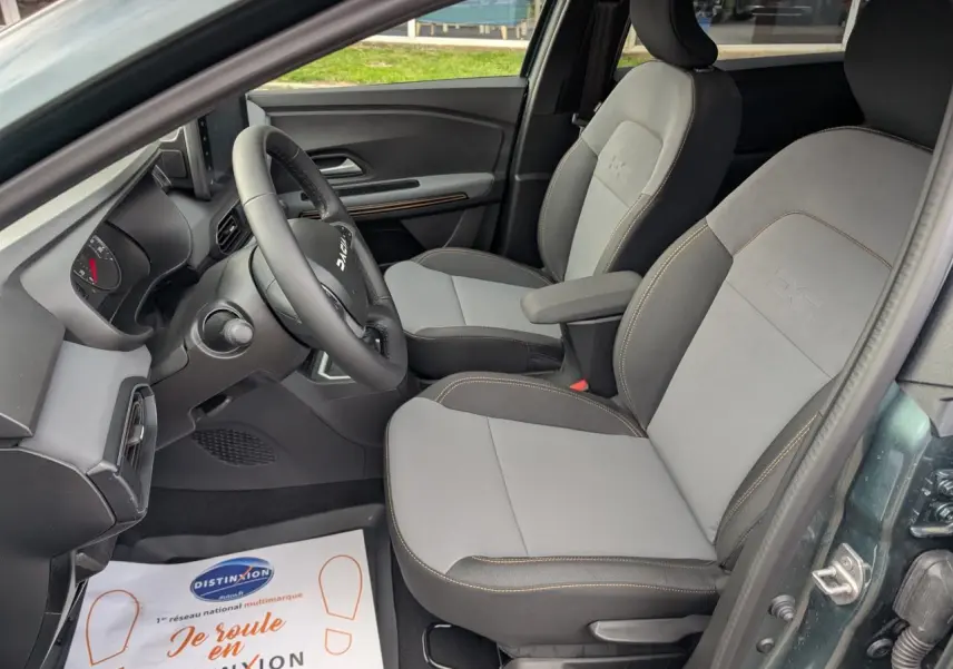 Vue intérieure côté conducteur du Dacia Jogger gris métallisé, sièges bi-matière gris et brun cuivré avec surpiqûres contrastées.