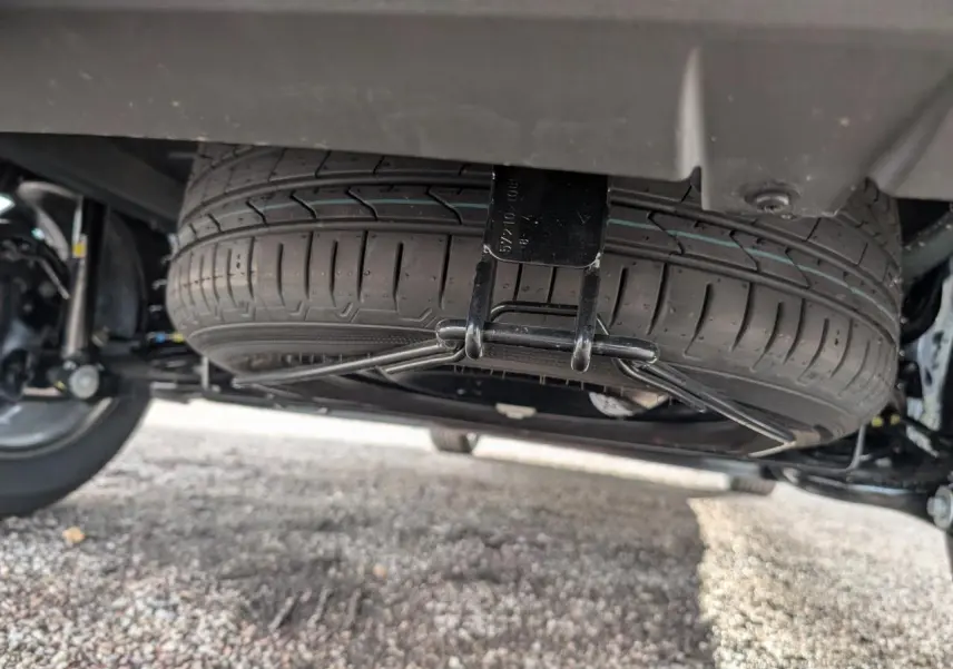 Gros plan sous le véhicule montrant la roue de secours suspendue du Dacia Jogger gris métallisé.