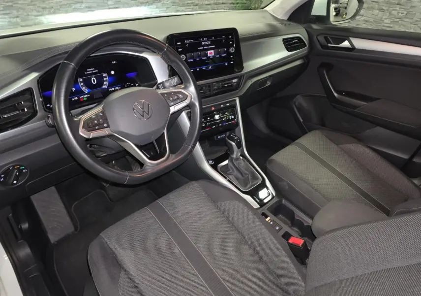 Vue intérieure côté conducteur du Volkswagen T-Roc 2022 avec tableau de bord digital et sellerie tissu noire.