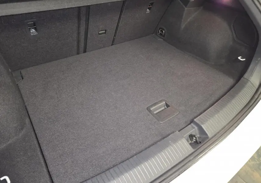 Coffre ouvert du Volkswagen T-Roc blanc, vue plongeante sur le tapis de sol noir et les fixations ISOFIX.