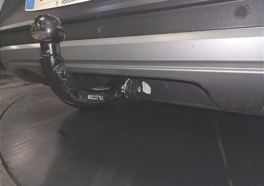 Gros plan sur l'attelage amovible noir fixé au pare-chocs arrière blanc du Volkswagen T-Roc 2022.