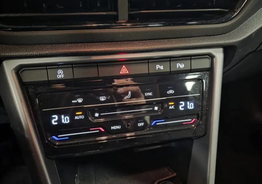 Gros plan sur la console centrale du Volkswagen T-Roc blanc, affichant la climatisation automatique bi-zone à 21°C.