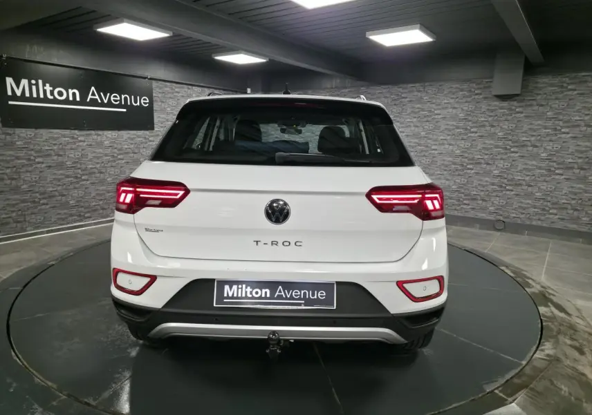 Vue arrière d'un Volkswagen T-Roc blanc avec feux LED allumés et dispositif d'attelage amovible visible.