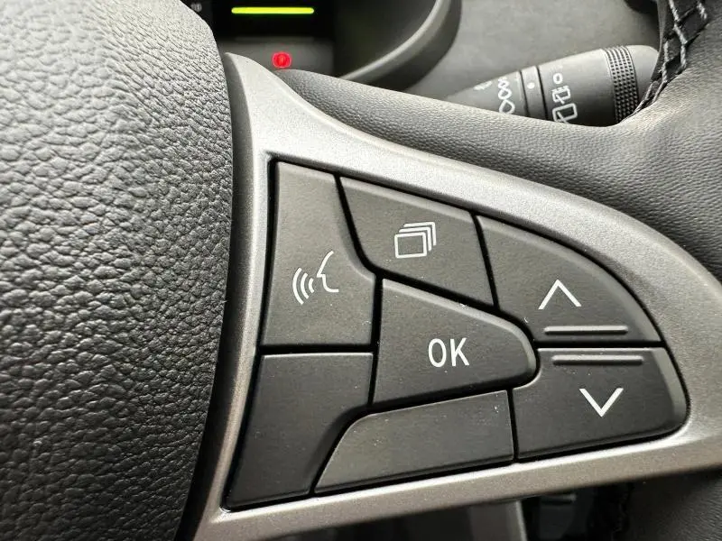 Gros plan sur les commandes multifonctions noires du volant du Dacia Jogger 1.6 hybrid noir nacré, côté gauche.