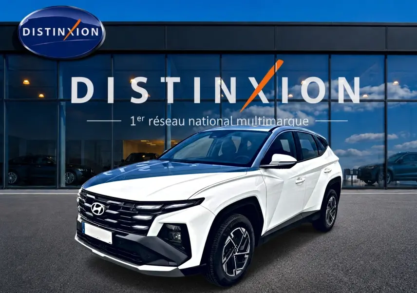 Hyundai Tucson blanc en 3/4 avant droit, avec calandre noire distinctive et jantes alliage 17 pouces.
