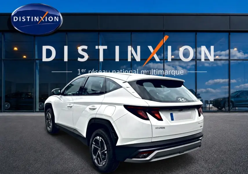 Vue 3/4 arrière droite d'un Hyundai Tucson blanc 2026 hybride, avec jantes alliage et feux arrière LED distinctifs.