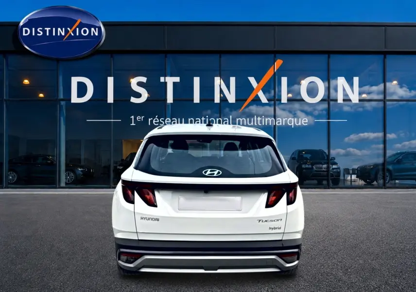 Vue arrière d'un Hyundai Tucson blanc hybride 2026, avec feux arrière sombres et logo Hyundai visible.