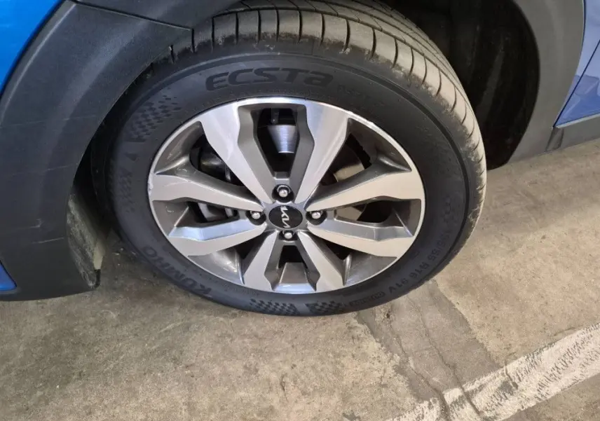 Gros plan sur la roue avant droite d’un KIA Stonic bleu 2024 avec jante alliage et pneu Kumho Ecsta.